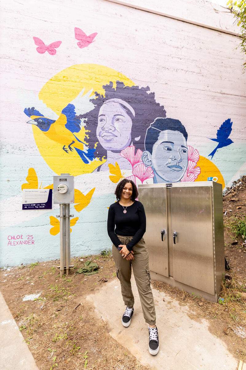 Artist standing in front of the new mural during the unveiling ceremony.